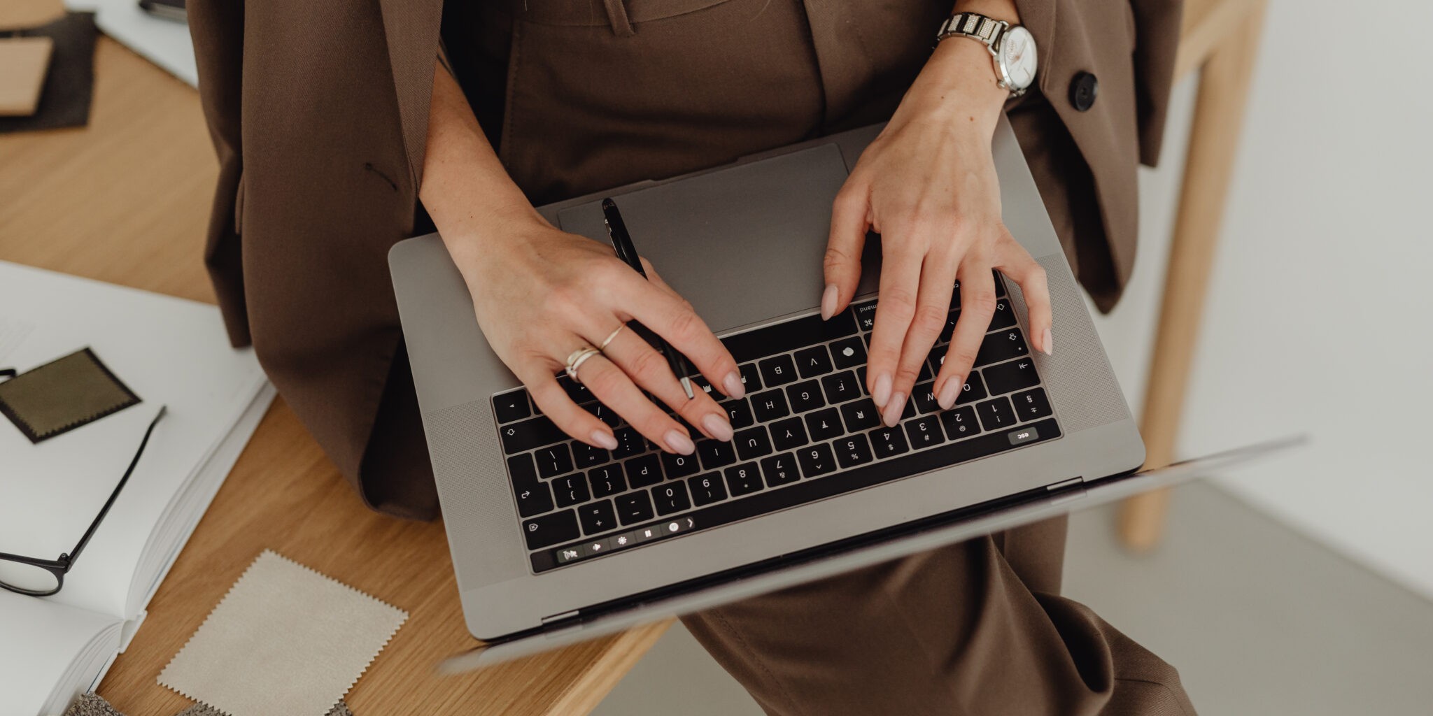 Freelancer typing on her laptop. This image introduces the blog post 'Branding Agency vs Freelance Brand Designer: Which is Right for Your Business?'
