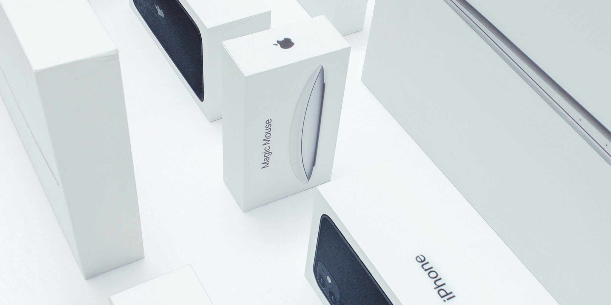 An image of several Apple product boxes featuring the iconic Apple logo prominently displayed on a plain background. The ample white space surrounding the logo is a distinctive brand asset, creating a clean and recognisable visual identity for Apple products.