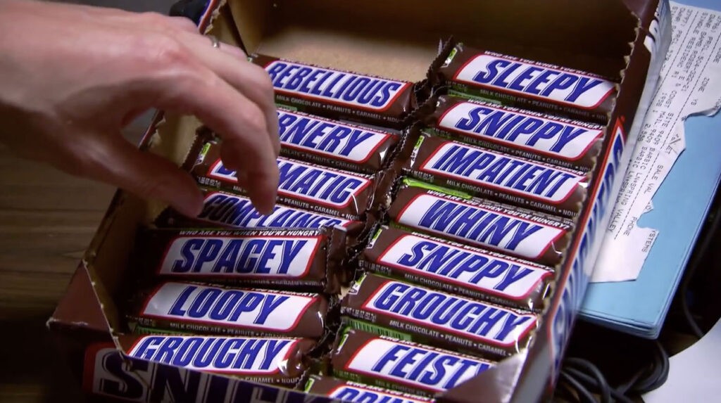 Das Bild zeigt, wie Snickers die Schriftart seines Logos durch Wörter ersetzt, die mit Hunger assoziiert werden: Ein Zeugnis dafür, dass die Logo Font ein unverwechselbares Marken-Asset ist