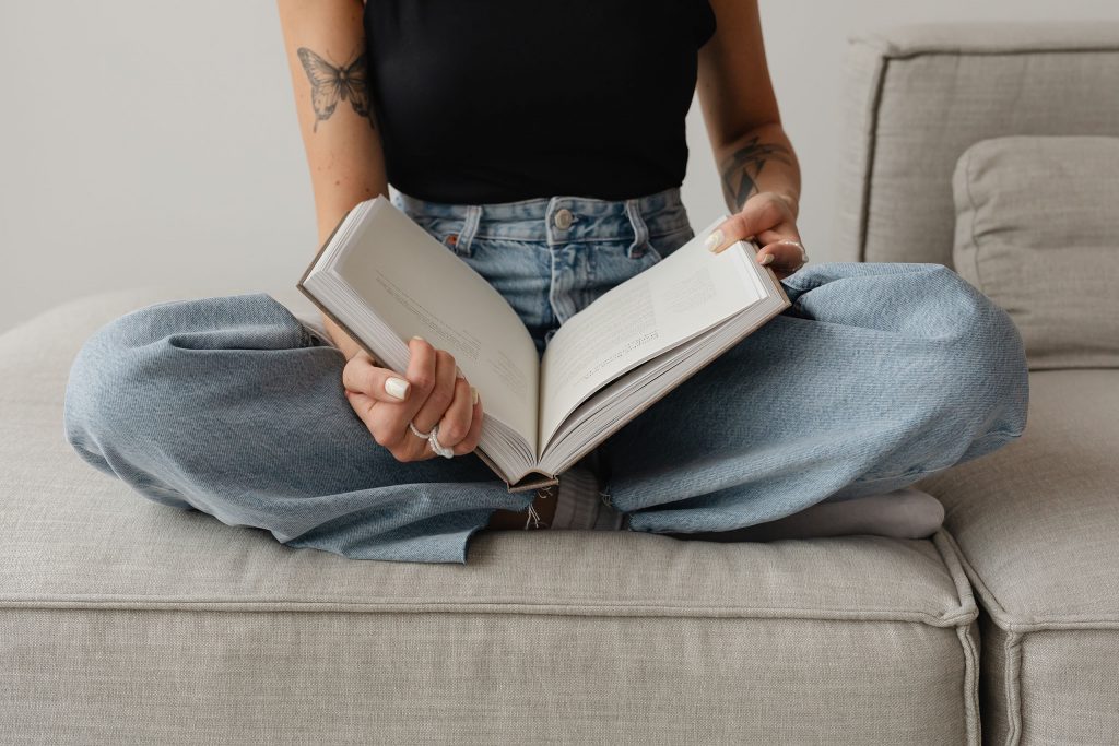 A woman sitting cross-legged holding a large book. This is the introduction to my article "Brand Glossary: 50 Branding Terms Explained"