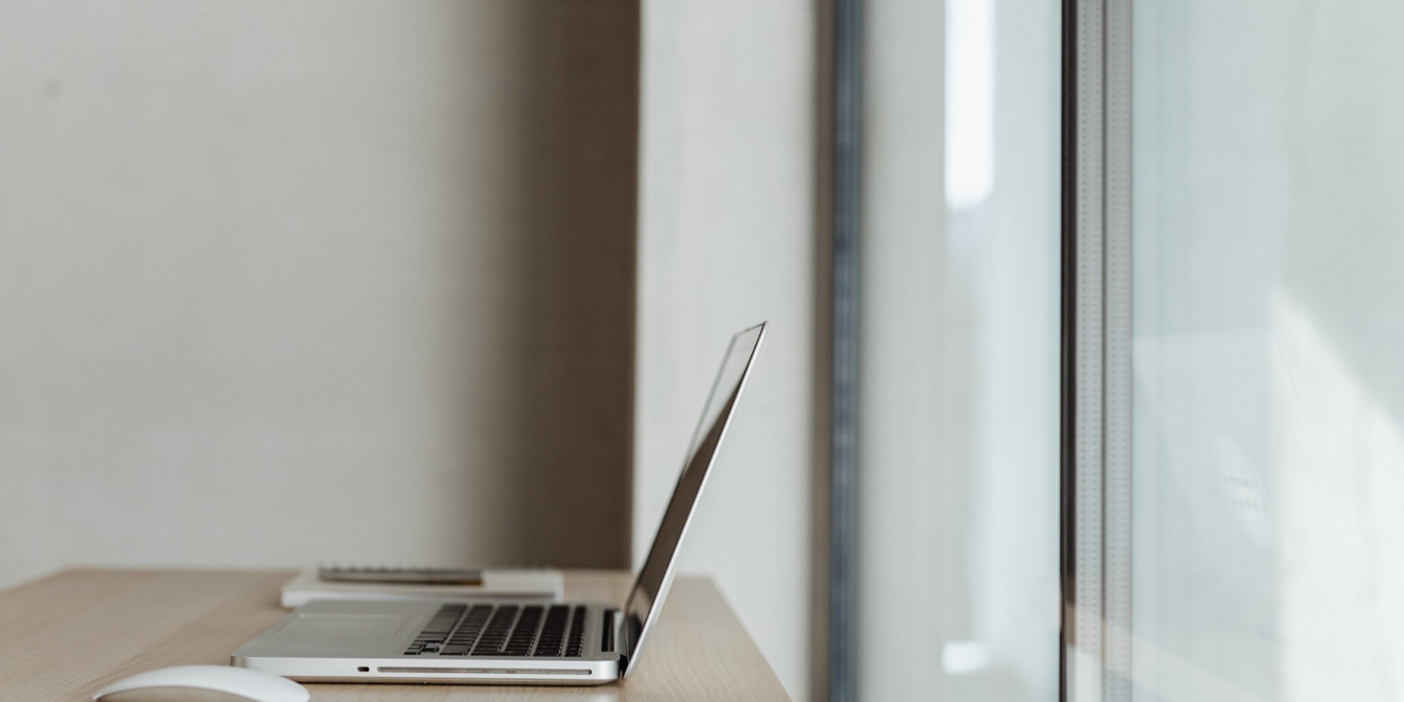 A laptop in front of a window. its the title image for a blog post about creating a great brand name.