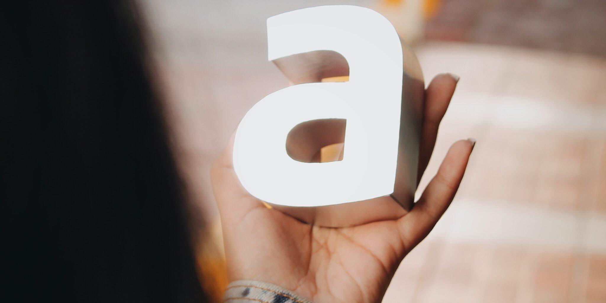 Woman holding the letter 'a'. This is the title image for a comprehensive article on choosing brand fonts.