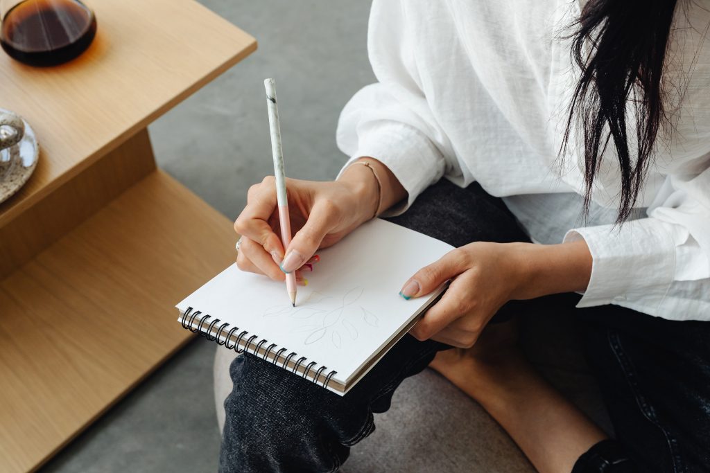 Woman writing something on a note pad. The image introduces my article "5 Ways a Tagline Can Help Your Brand"