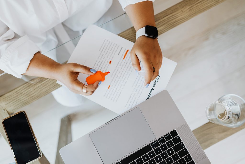 A woman highlights a document and sits next to a laptop. This is an introduction for the article "10 tips business website that converts"