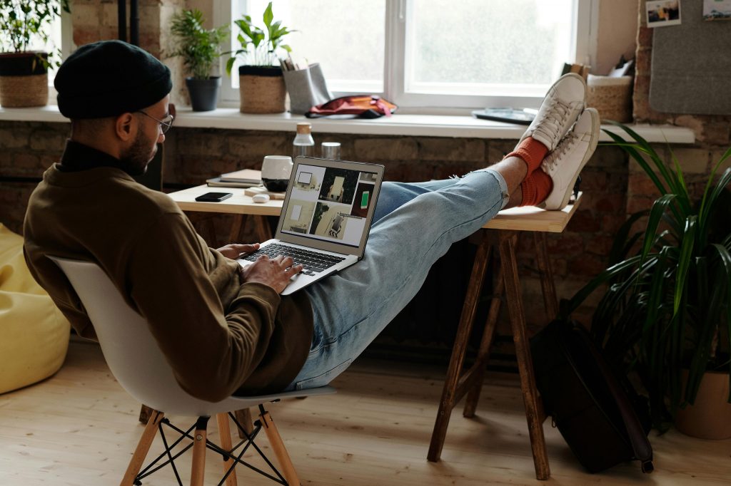 Intro image for an article on the best branding tools for designers and small business owners—featuring a man on a laptop with feet up, facing a window.