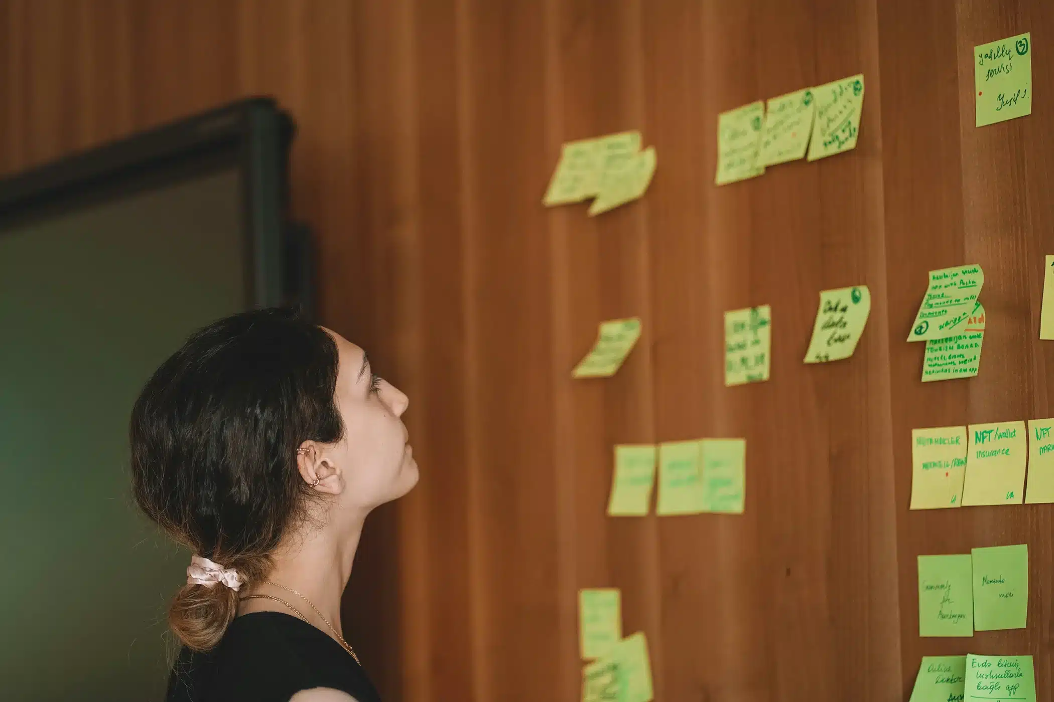 Woman looking at a wall of colorful sticky notes during a brand strategy workshop—part of the brand strategy process.