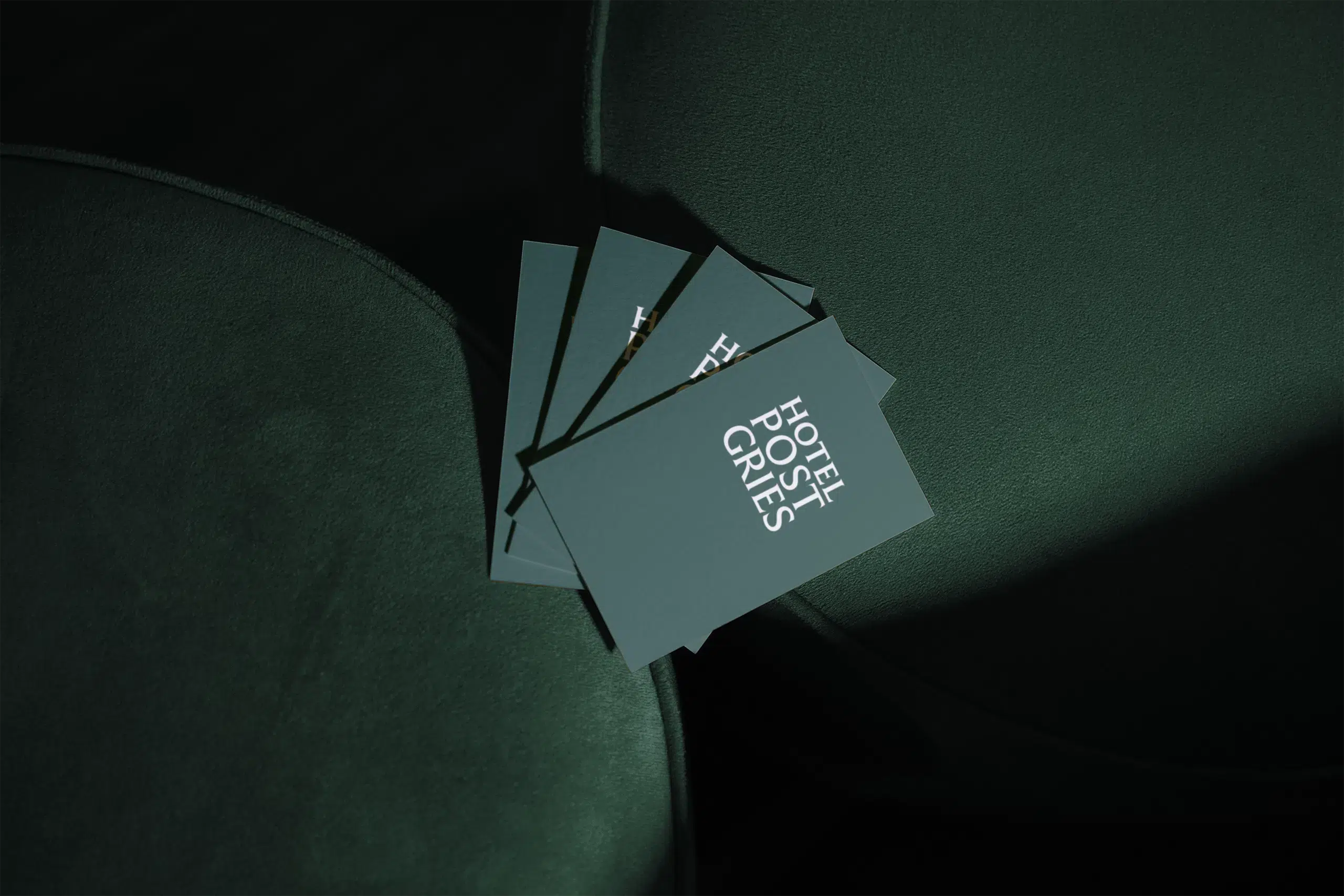 Mockup of business cards designed for Hotel Post Gries, showing white print on a green board