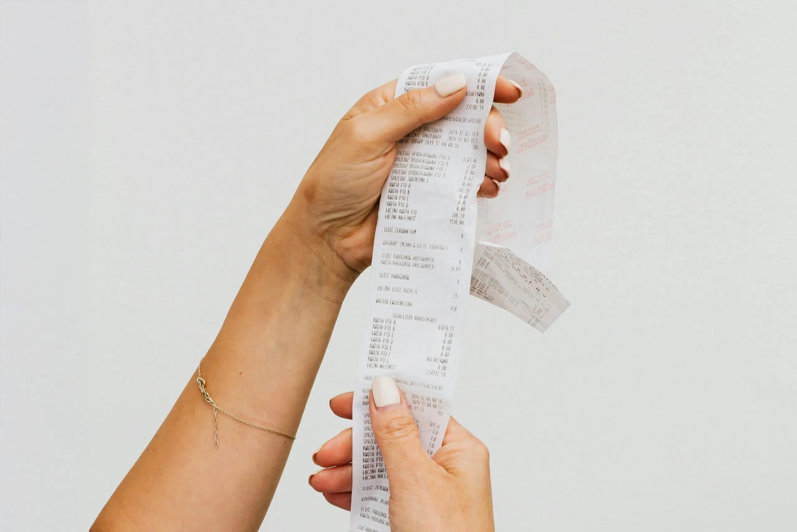 Hands holding a receipt against a plain white background. This is the introduction image for an article about the pricing and brand perception.