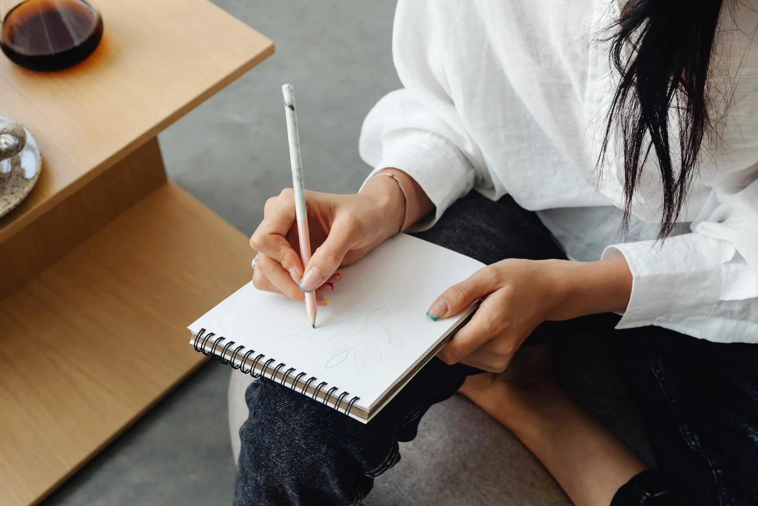Woman writing something on a note pad. The image introduces my article "5 Ways a Tagline Can Help Your Brand"