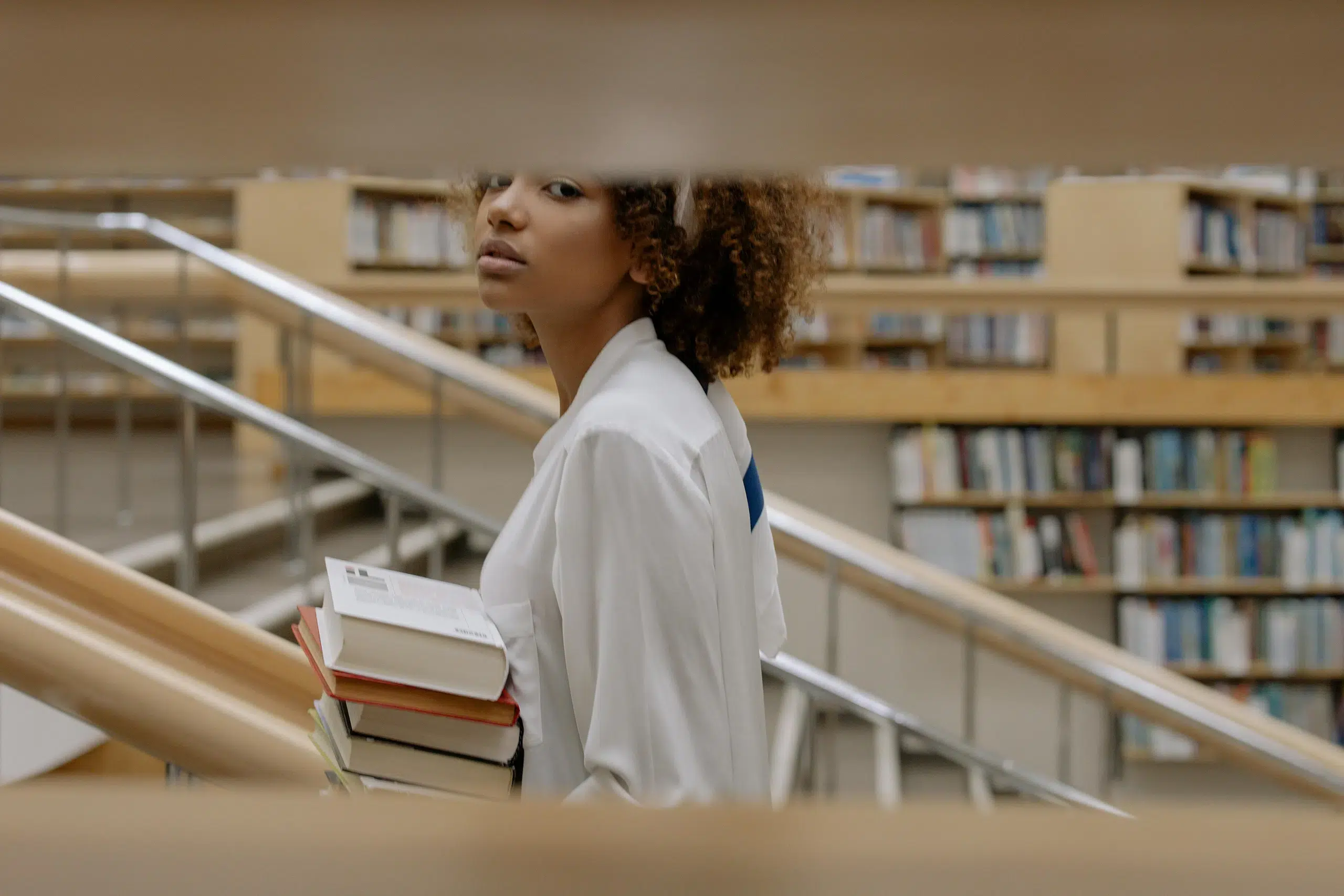 A girl in a library carrying a pile of books. This is the intro to an article on alternatives to branding books