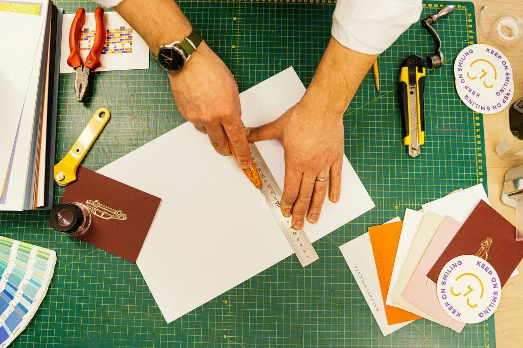 Arbeitsbereich mit Händen auf einer Schneidematte, umgeben von Branding-Tools, als Illustration für einen Artikel über die besten Branding-Tools.