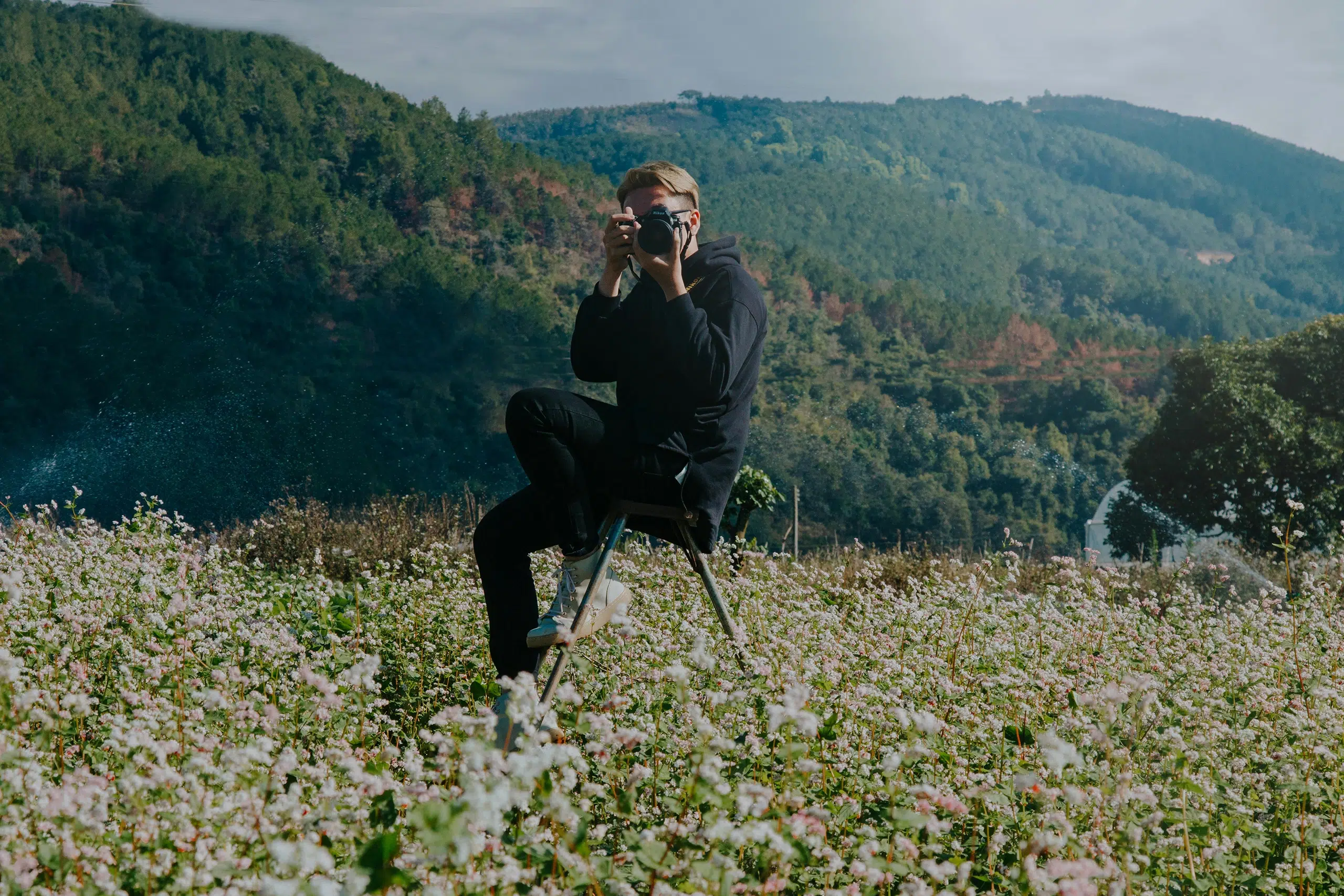 A person sitting on a stool in nature, looking through a camera—symbolising clarity, perspective, and purpose in capturing brand values.