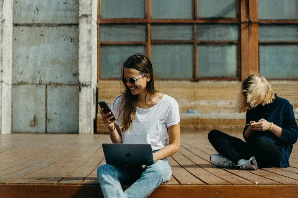 Zwei Frauen sitzen draußen und arbeiten an ihren Handys als Einleitung zu dem Artikel, warum es wichtig ist, die Zielgruppe zu identifizieren, wenn es um Branding geht.