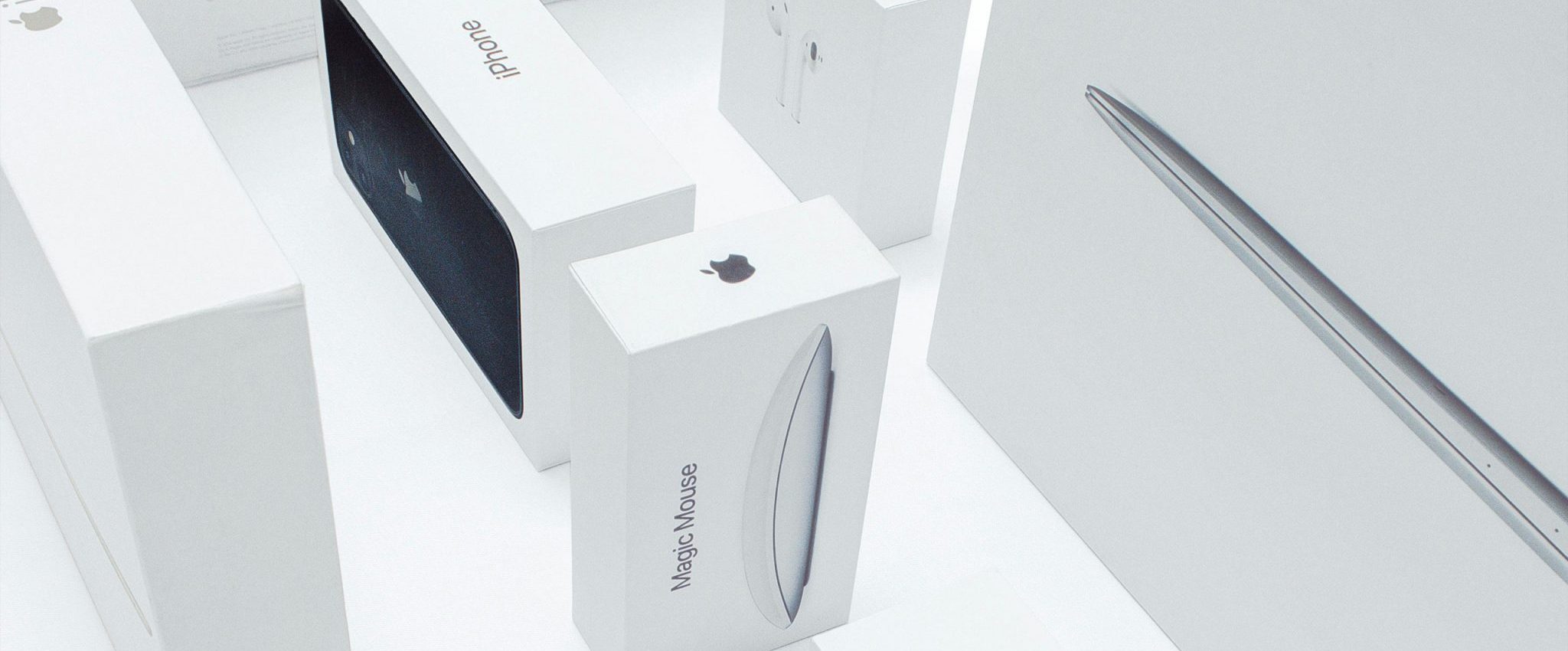 Several Apple product packagings featuring the iconic Apple logo prominently displayed on a plain background. The ample white space surrounding the logo is a distinctive brand asset, creating a clean and recognisable visual identity for Apple products.