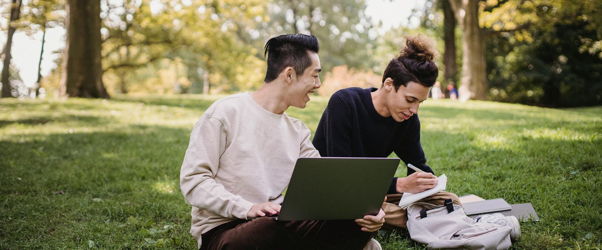 Zwei Männer sitzen in einem Park, machen ein Brainstorming und schreiben. Dieses Bild leitet einen Blogbeitrag namens „Was ist eine Tagline plus 50+ inspirierende Beispiele“ ein.