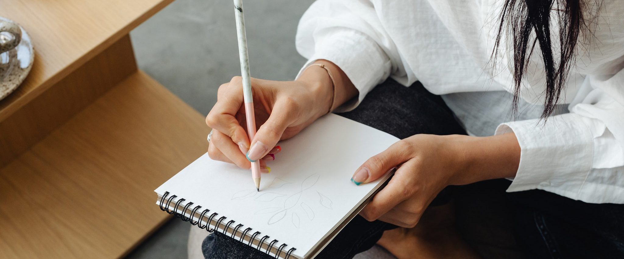 Woman writing something on a note pad. The image introduces my article "5 Ways a Tagline Can Help Your Brand"