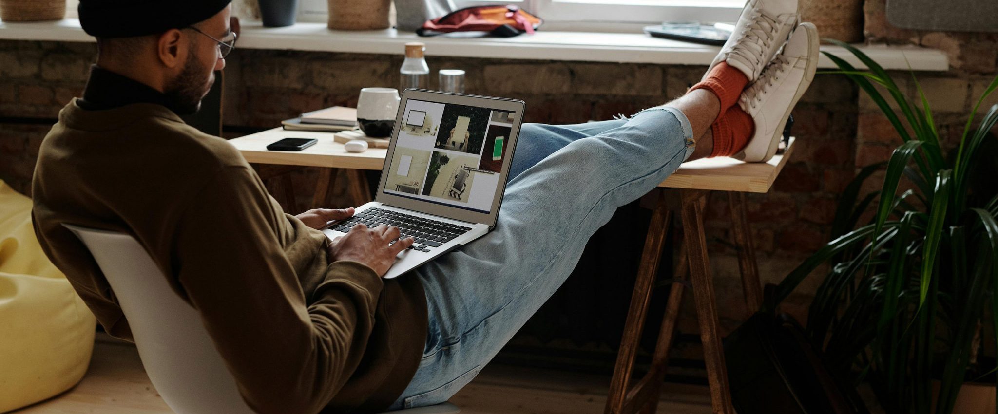 Intro image for an article on the best branding tools for designers and small business owners—featuring a man on a laptop with feet up, facing a window.