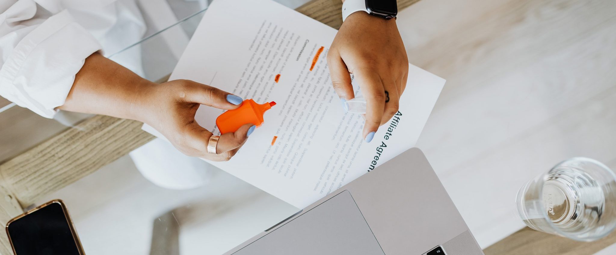 Eine Frau markiert ein Dokument und sitzt neben einem Laptop. Dies ist eine Einleitung für den Artikel „10 Tipps für ein Website-Design, das zu Conversions führt“.