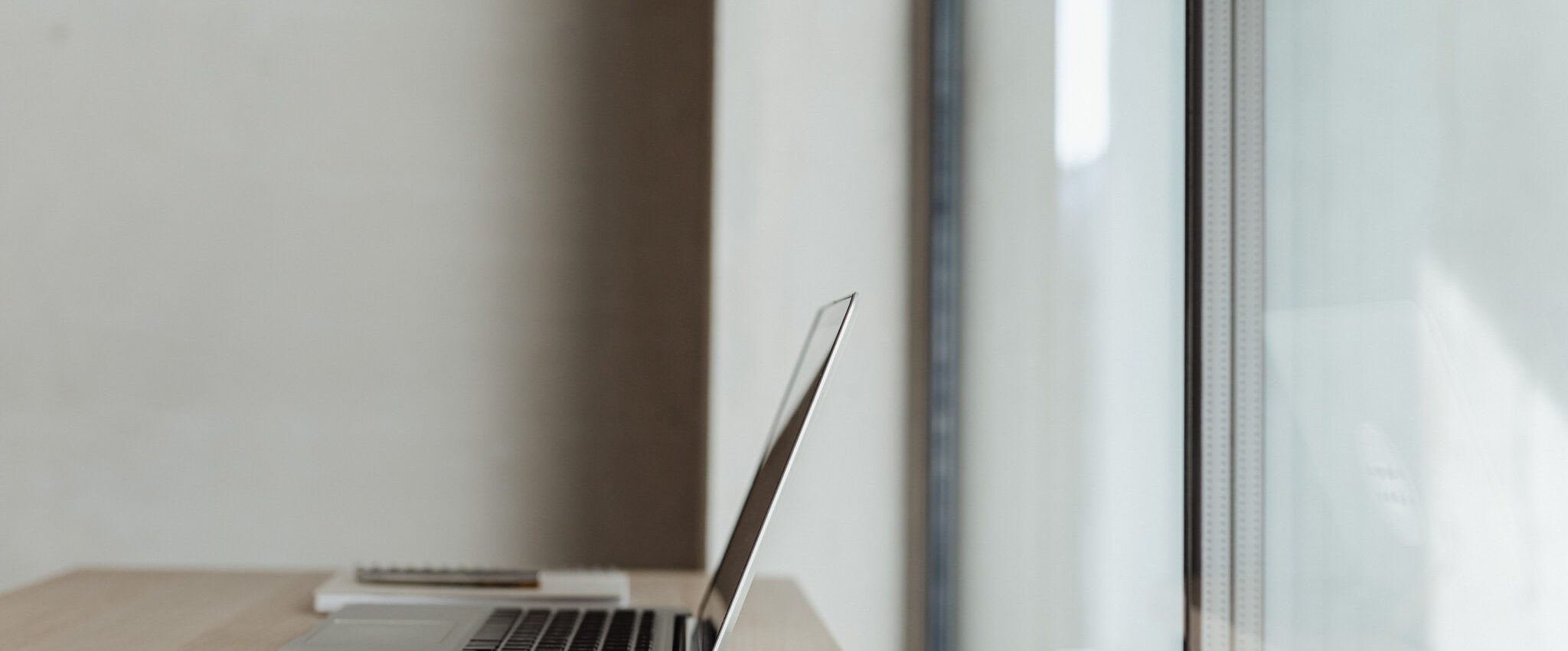 A laptop in front of a window. its the title image for a blog post about creating a great brand name.