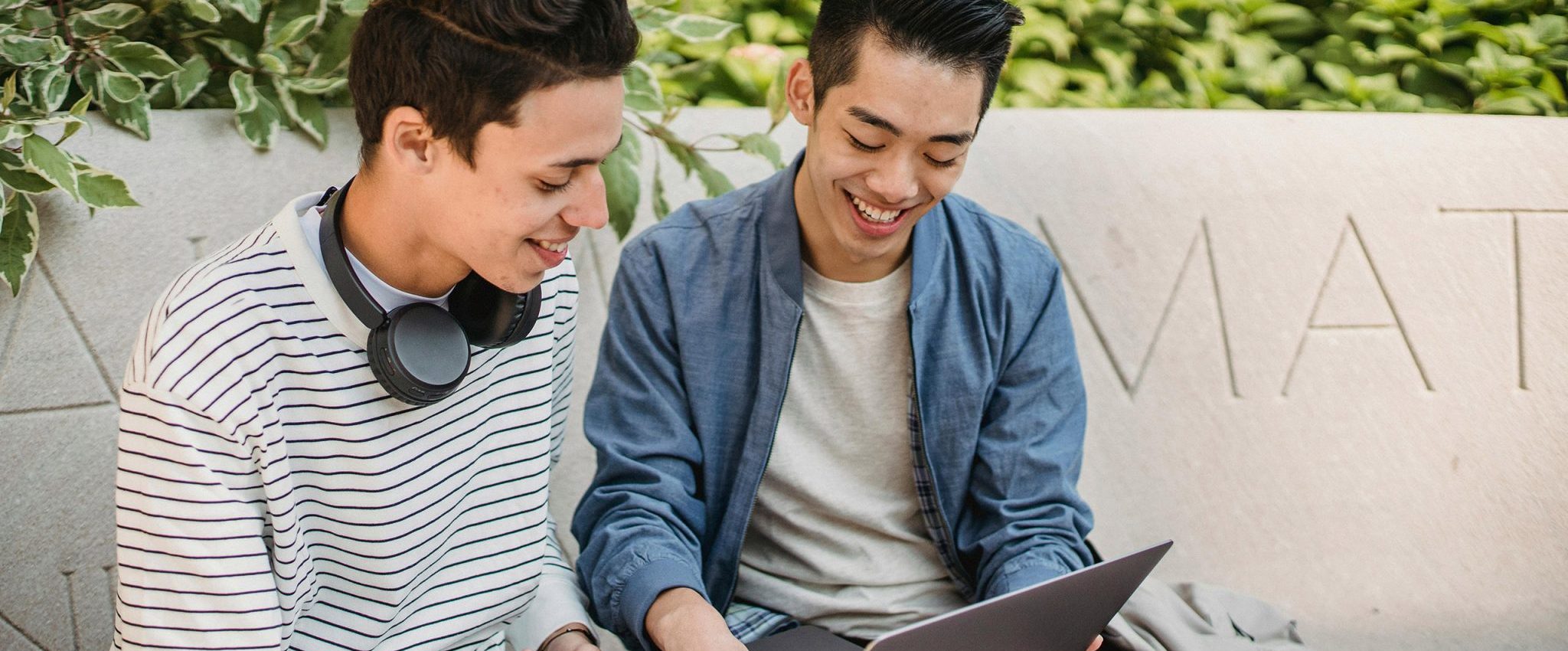 Two guys working on a laptop outside, looking happy. This is an intro into an article about employer branding.